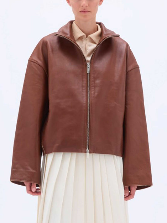 Femme portant The Bonded Leather Jacket Brown, veste en cuir marron à col montant et coupe droite, manches longues et épaules tombantes, vue de face.